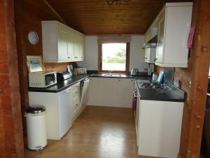 a small kitchen with white cabinets and a window at Chestnut Lodge in Pilling