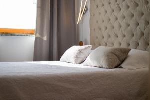een slaapkamer met een bed met 2 kussens en een raam bij Apartmani VILLA KALINIC in Njivice