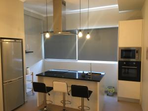 a kitchen with a black counter and some chairs at Cantinho do Sonho in Maia
