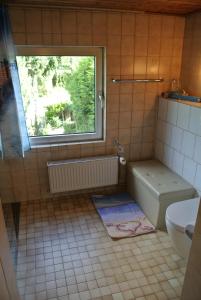 a bathroom with a window and a tub and a toilet at Ferienwohnung zur Mühle in Sotzweiler