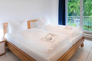 - une chambre avec 2 lits avec des draps blancs et une fenêtre dans l'établissement Haus am Südstrand Stranddistel, à Sellin