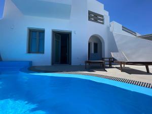 a villa with a swimming pool and a house at Amphitrite Suites Santorini in Vóthon