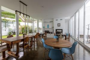 a dining room with tables and chairs and large windows at My Angra Charming House in Angra do Heroísmo