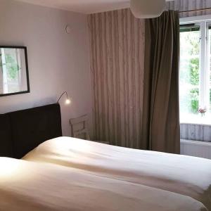 1 dormitorio con cama blanca y ventana en Sörgårdens gästlägenhet 1-4 personer, en Köping