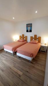 two beds in a bedroom with wood floors at Les Muches in Bouzincourt