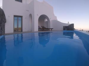 - une piscine d'eau bleue dans un bâtiment dans l'établissement Amphitrite Suites Santorini, à Vóthon