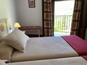 a bedroom with a bed and a window with a balcony at Hostal Atalaya en Capileira CB in Capileira