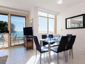een eetkamer met een tafel en stoelen en een televisie bij Little Hut 1 Spectacular Water Views NBN and Air Conditioned in Nelson Bay
