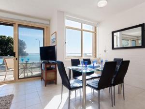 a dining room with a table and chairs and a television at Little Hut 1 Spectacular Water Views NBN and Air Conditioned in Nelson Bay