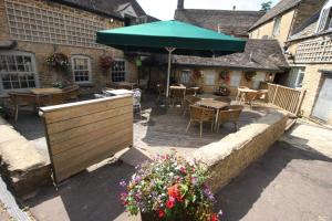 a patio with tables and a green umbrella at The Kings Arms Hotel in Chipping Norton