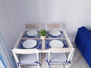 una mesa con 2 sillas y platos y una planta en Conil Centro & Playa, descanso perfecto, Aire Ac y WIFI -SOLO FAMILIAS Y PAREJAS- en Conil de la Frontera