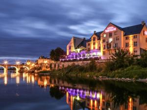 une ville éclairée la nuit à côté d'une rivière dans l'établissement Mercure Bords de Loire Saumur, à Saumur