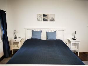 ein Schlafzimmer mit einem Bett mit blauen Kissen und 2 Tischen in der Unterkunft Hűvösvölgy Vendégház in Lókút