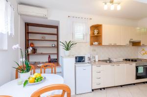 una cocina con armarios blancos y una mesa con un bol de fruta en Holiday Home Hope, en Mokošica