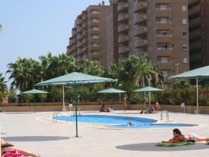 um grupo de pessoas deitadas em torno de uma piscina com guarda-sóis em Costa Caribe III em Oropesa del Mar