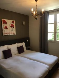 1 dormitorio con 2 camas y lámpara de araña en Logis Hôtel Restaurant La Bastide en Villefranche-du-Périgord