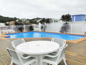 a white table and chairs on a deck with a pool at Nelson Towers, 9,71a Victoria Parade - unit in the heart of Nelson Bay with water views, air conditioning and Wi-Fi in Nelson Bay
