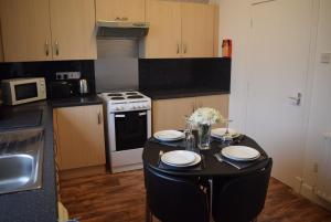 d'une cuisine avec une table avec des assiettes et des fleurs. dans l'établissement Kelpies Serviced Apartments McDonald- 2 Bedrooms, à Falkirk