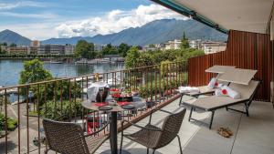 a balcony with a table and chairs and a view of the water at Hotel Lago Maggiore - Welcome! in Locarno