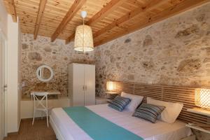 een slaapkamer met een bed en een stenen muur bij River View in Prasiaí +27 foto's