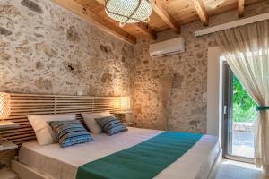 een slaapkamer met een bed en een stenen muur bij River View in Prasiaí