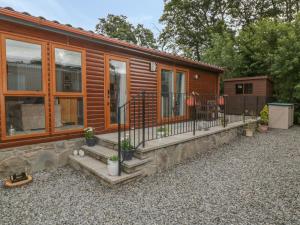 a log cabin with a porch and a fence at Daisy Lodge in Auchterarder