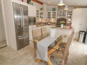 a kitchen with a dining table and a stainless steel refrigerator at Daisy Lodge in Auchterarder