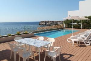 a deck with a table and chairs next to a swimming pool at Villa TURQUESA MAR in Cala en Forcat