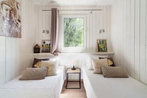 - un salon avec deux lits blancs et une fenêtre dans l'établissement Les minis homes du Bugey - Eco-lodge Nature ,un refuge en hyper centre, à Ambérieu-en-Bugey