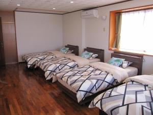 a group of four beds in a room at ホテル ハイビスヤブ in Nago