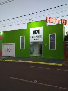a green building with a hotel sign on a street at Angelu's Hotel in Nova Andradina