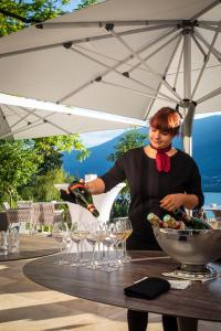 eine Frau, die unter einem Regenschirm steht und Weingläser gießt in der Unterkunft Hôtel L'Incomparable by Les Etincelles in Tresserves