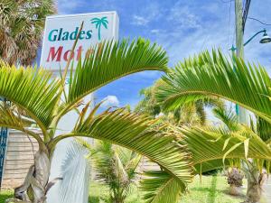 a sign for a clades motel with palm trees at Glades Motel - Naples in Naples