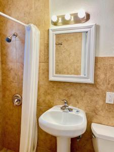 a bathroom with a sink and a mirror and a shower at Glades Motel - Naples in Naples