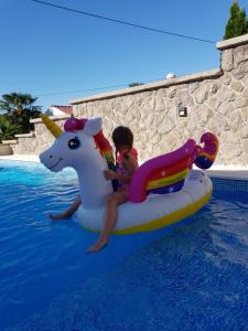 a little girl riding on a unicorn raft in the water at Ivezić in Njivice