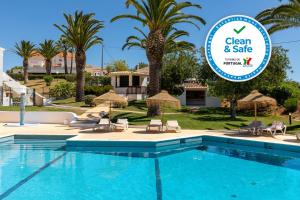 a pool at a villa with a sign that says clean and safe at Parque Monte Verde in Albufeira