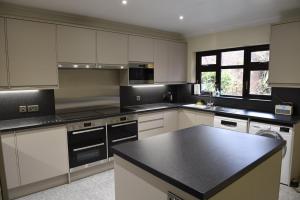 a kitchen with white cabinets and a black counter top at Toothbrush Rooms at Lattice Lodge - Self Catering & EV Recharging in Ipswich