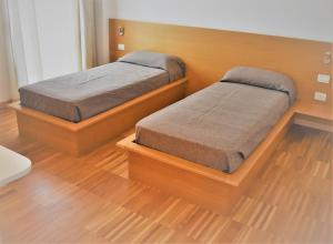 2 Betten in einem Zimmer mit Holzböden in der Unterkunft Residence SchioHotel in Schio