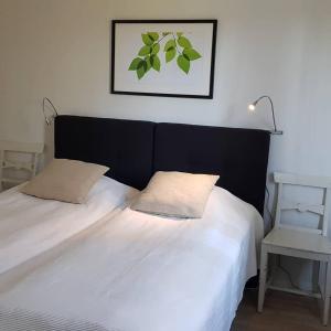 1 cama con sábanas blancas y cabecero negro en Sörgårdens gästlägenhet 1-4 personer, en Köping
