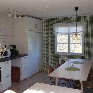 een keuken met een tafel en stoelen en een raam bij Sörgårdens gästlägenhet 1-4 personer in Köping