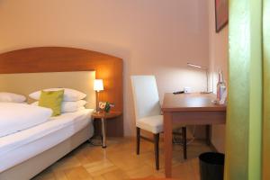 
a bedroom with a bed, desk and a lamp at Hotel Rappensberger in Ingolstadt
