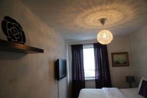1 dormitorio con cama, ventana y lámpara de araña en Vingåker Hotell en Vingåker