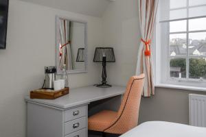 a bedroom with a desk with a mirror and a chair at Balfour Arms in Sidmouth