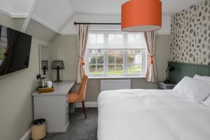 a bedroom with a bed and a desk and a window at Balfour Arms in Sidmouth