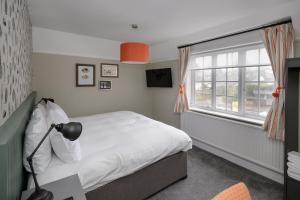 um quarto com uma cama branca e uma janela em Balfour Arms em Sidmouth