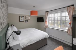 a bedroom with a white bed and a window at Balfour Arms in Sidmouth