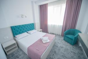 エフォリエ・ノルドにあるHotel Olgutaのベッドルーム1室(ベッド1台、青い椅子付)