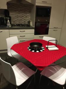 una mesa roja con sillas blancas y una olla negra en ella en Casa Elite, en Bardolino