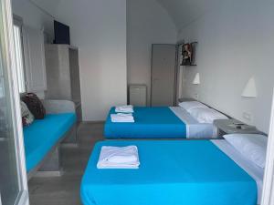two beds in a small room with blue beds at Hotel Hellas in Fira