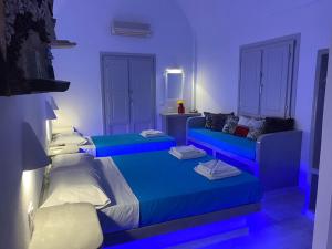 a blue room with two beds and a couch at Hotel Hellas in Fira